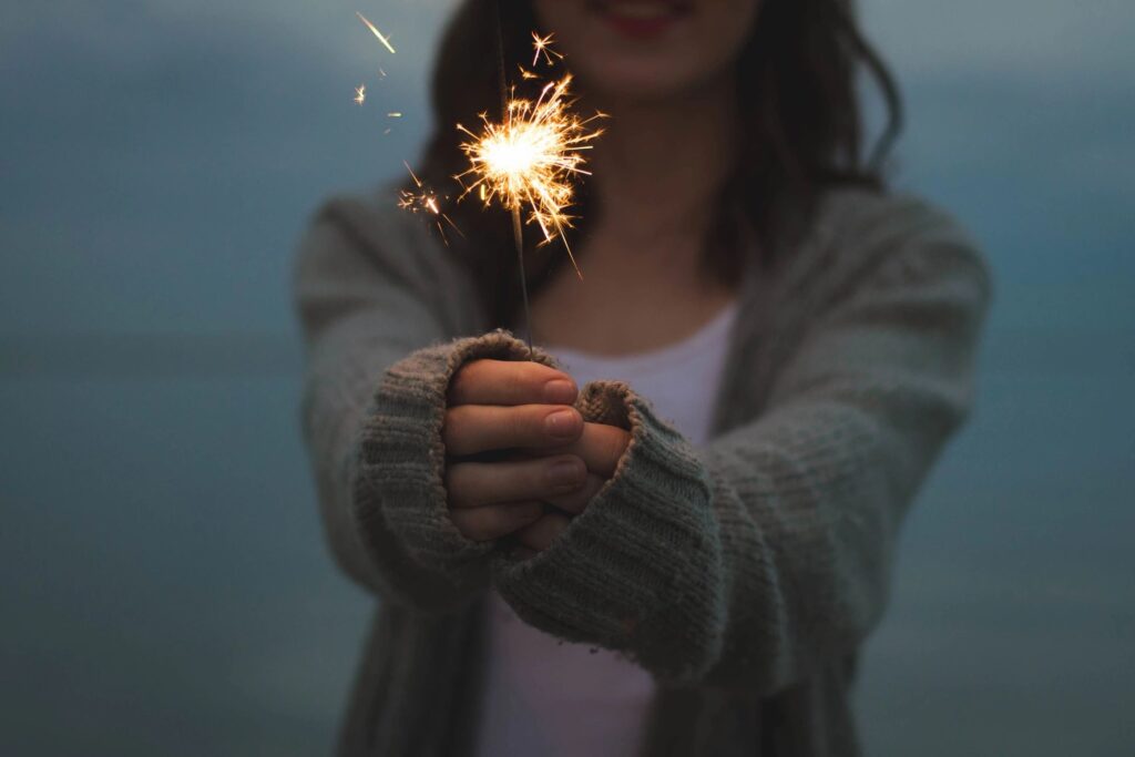 Person holding a lit sparkler in hands.